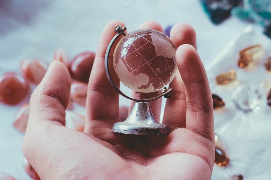 Pessoa segurando um globo terrestre em miniatura, de vidro.
