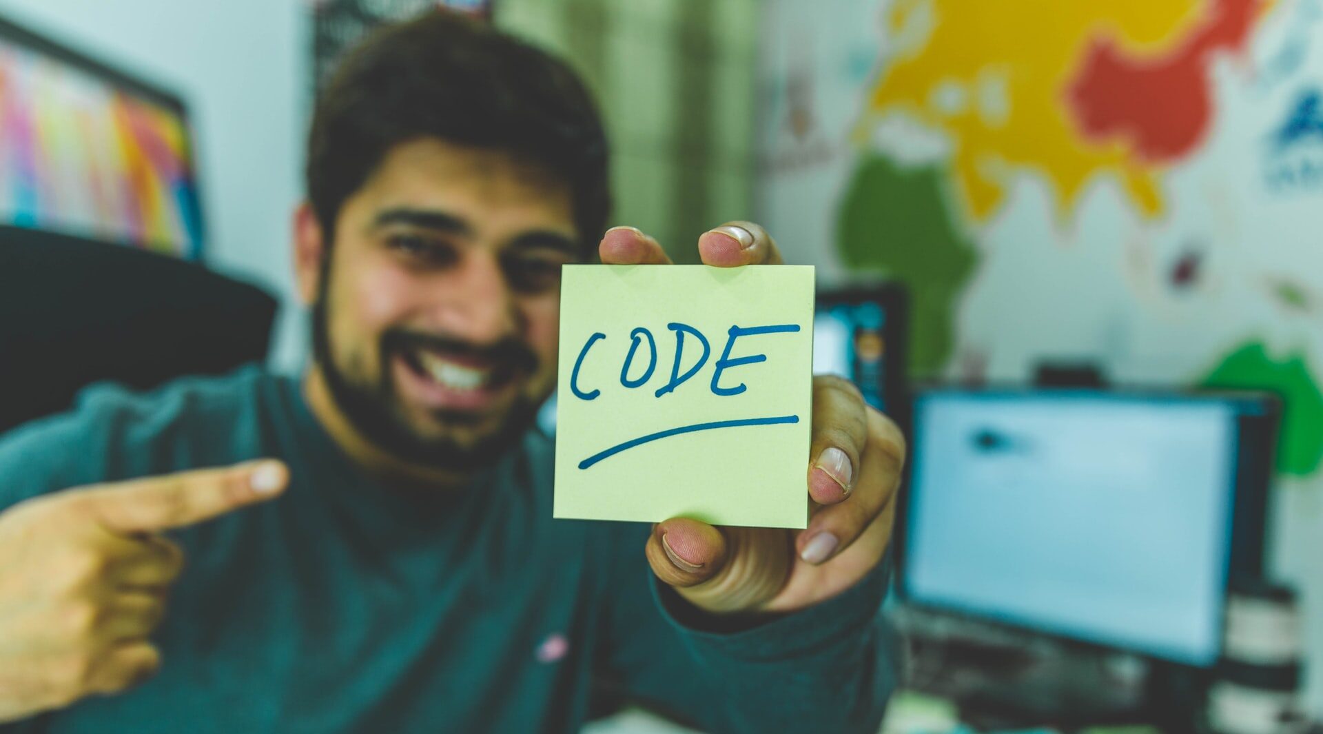 Desenvolvedor apontando orgulhosamente para a palavra CODE, ilustrando o artigo sobre Dia do Programador