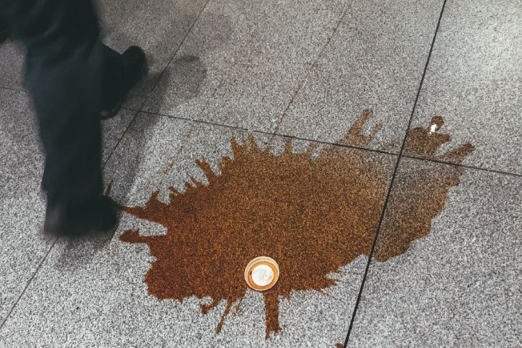 Copo de café derramado no chão.