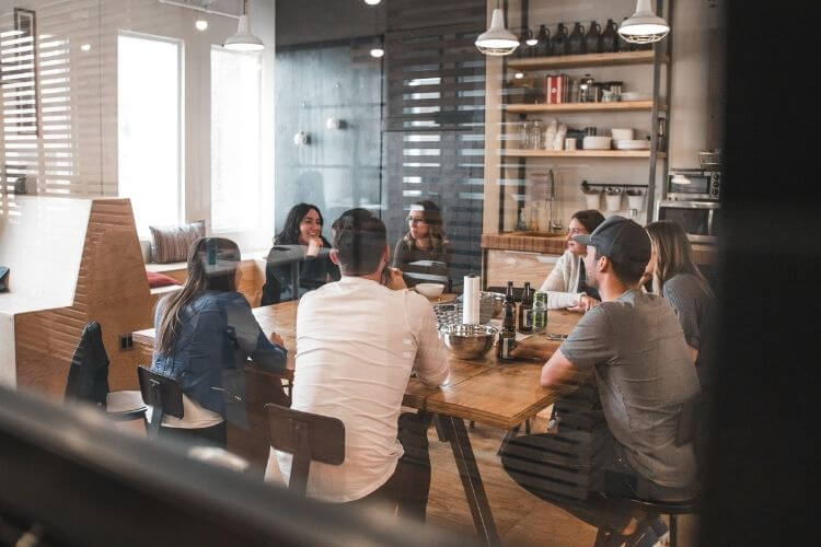 Pessoas sentadas à mesa de trabalho, conversando.